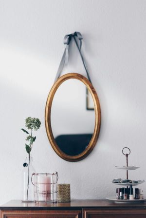 oval mirror hanging above a dresser with feminine decor